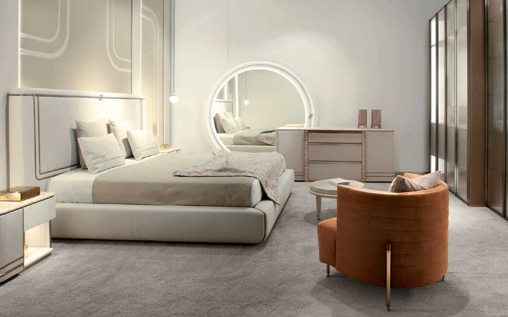 Modern bedroom with upholstered bed, backlit round mirror and velvet armchair